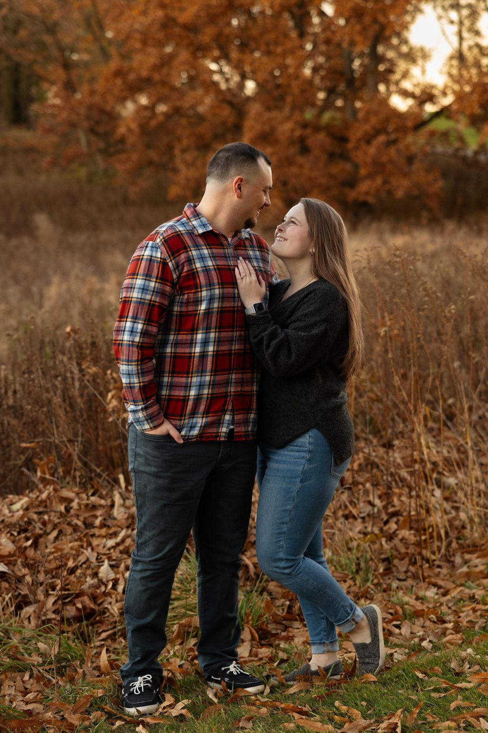 A tender moment between a couple in casual attire surrounded by fall colors.