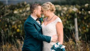 Close-up wedding photo showing tender embrace against scenic outdoor background.