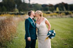 A romantic wedding moment captured in a natural outdoor setting with tall grass.