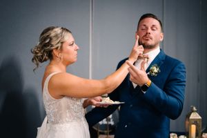 Bride and groom share a fun moment while tasting their wedding cake.