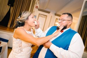 Wedding couple playfully feeding each other cake at their reception in an elegant venue.