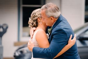 Intimate embrace captured during wedding first look moment outside building.