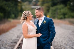 Happy couple share a loving moment on train tracks during their wedding day.
