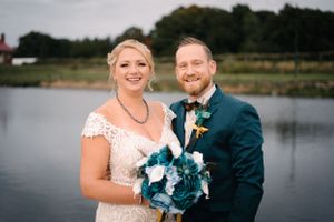 Wedding portrait captures genuine smiles by lakeside with natural scenery.