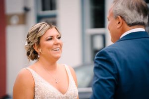 An emotional outdoor wedding moment showing a bride in a white dress sharing a joyful expression.