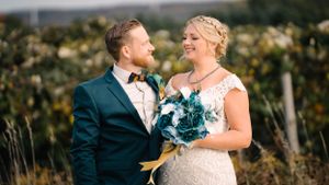 Romantic wedding moment captured in outdoor setting with natural foliage backdrop.