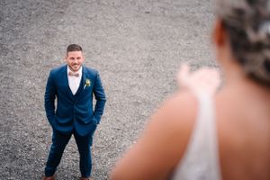 Wedding portrait session with groom posing against gravel background.