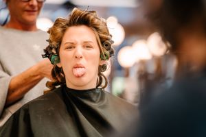 Client making silly face during haircut at modern salon.