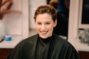 Smiling client in black cape during salon appointment.