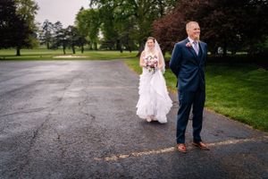 A wedding couple stands apart during an emotional first look moment on a rainy day.
