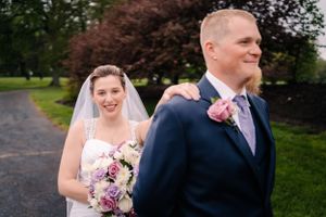 A wedding couple shares a joyful moment together on a path surrounded by greenery.