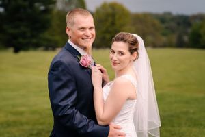Newlyweds share tender moment on grassy lawn during wedding photoshoot.