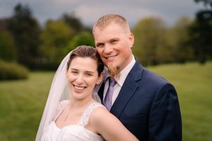 Joyful wedding couple smiles together in outdoor setting.