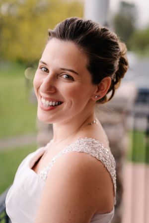 Bride wearing lace detail dress smiles in natural lighting.
