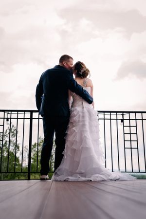 Silhouette of couple embracing on balcony during sunset wedding photo.
