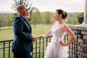 A couple shares a joyful moment on an outdoor deck during their wedding day celebration.