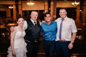 Wedding party poses together for a group photo at an indoor reception venue.