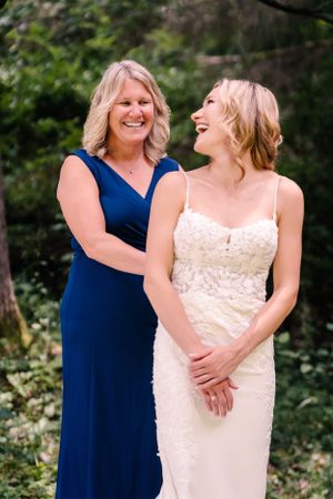 Two people sharing a candid laughing moment at an outdoor wedding.