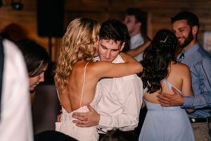 Couples embrace while slow dancing at an indoor wedding reception with warm lighting.