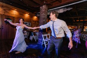 Wedding guests dance energetically on a rustic wooden dance floor with mood lighting.