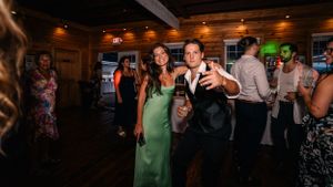 Guests enjoy dancing and socializing at a rustic indoor wedding reception venue.