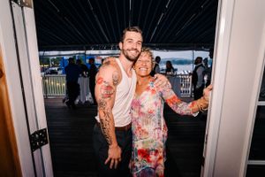 A couple poses together on an outdoor deck at dusk during a celebration.