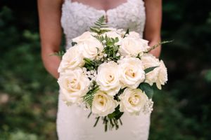 Close-up of a bridal bouquet featuring cream-colored roses and delicate greenery.