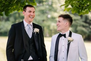 Two people in formal attire share a candid laughing moment during an outdoor photo session.