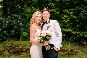 Romantic garden wedding portrait with couple holding white rose bouquet.