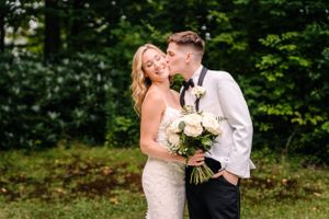 Intimate garden wedding moment with couple sharing sweet moment by green foliage.