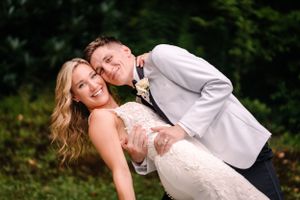 Playful wedding couple sharing lighthearted moment in outdoor setting.