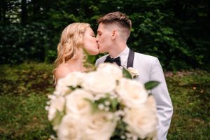 Romantic kiss captured with soft focus white roses in foreground.