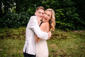 Candid laughing moment between newlyweds in garden setting.