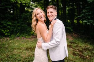 Joyful wedding couple sharing a candid laughing moment in a garden setting.