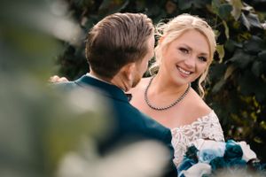 Candid moment of bride wearing lace dress and pearl necklace during vineyard wedding.