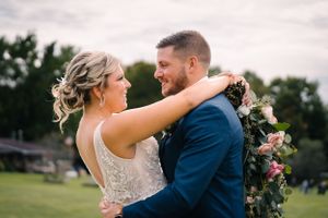 Happy couple embraces during outdoor wedding celebration in natural setting.