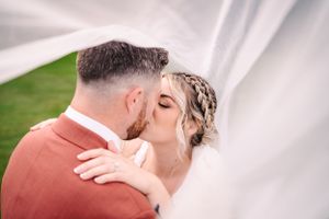 Wedding portrait showing close-up of tender moment against green outdoor backdrop.