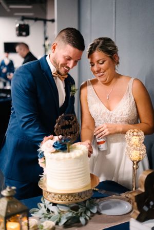 Newlyweds sharing a joyful moment while cutting their white wedding cake.