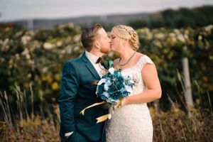 Intimate wedding portrait showing couple sharing tender moment with blue bouquet.