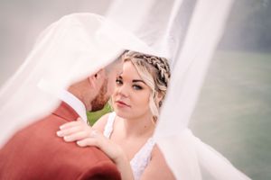 Artistic close-up wedding photo with flowing white veil detail.