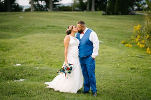 Romantic couple shares intimate moment on grassy hillside during wedding photoshoot.