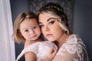An intimate indoor portrait showing matching white lace dresses and delicate styling.