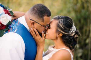 Intimate moment between newlyweds with romantic bouquet of red and white flowers.