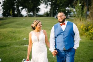Couple holding hands and smiling during outdoor wedding photoshoot.
