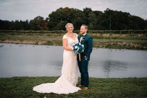 Newlyweds share a joyful moment together by a peaceful lakeside setting.