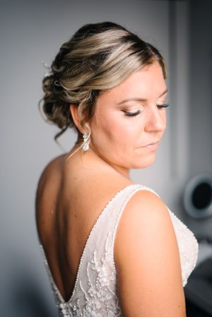 Elegant bridal portrait showing detailed lace back of wedding dress and upswept hairstyle.