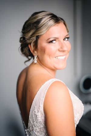 Portrait of bride wearing lace gown with delicate beading and drop earrings.