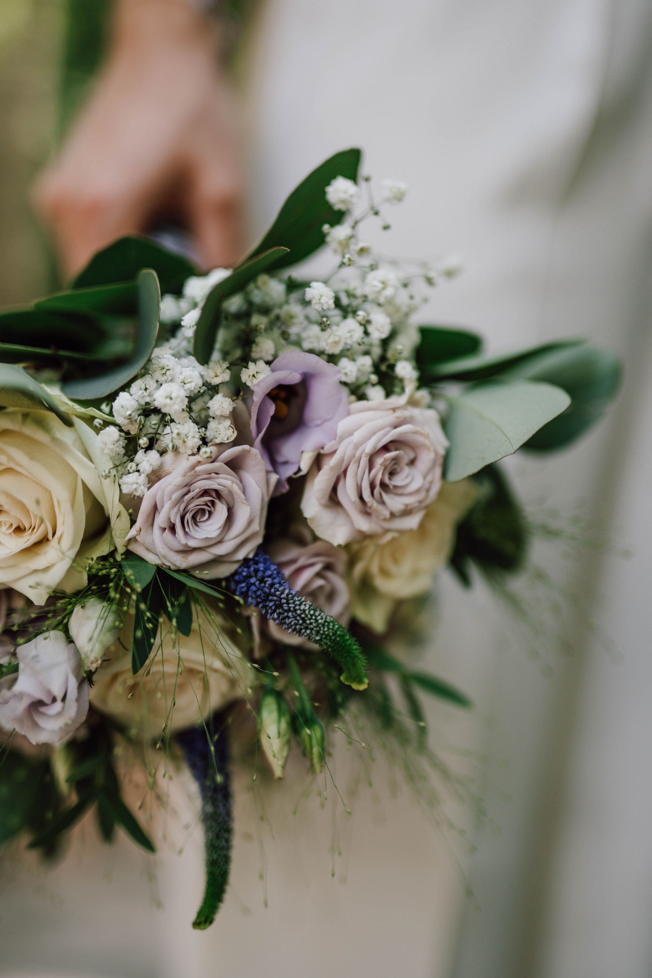 Elegant wedding bouquet with roses, baby's breath and greenery in soft pastel colors.