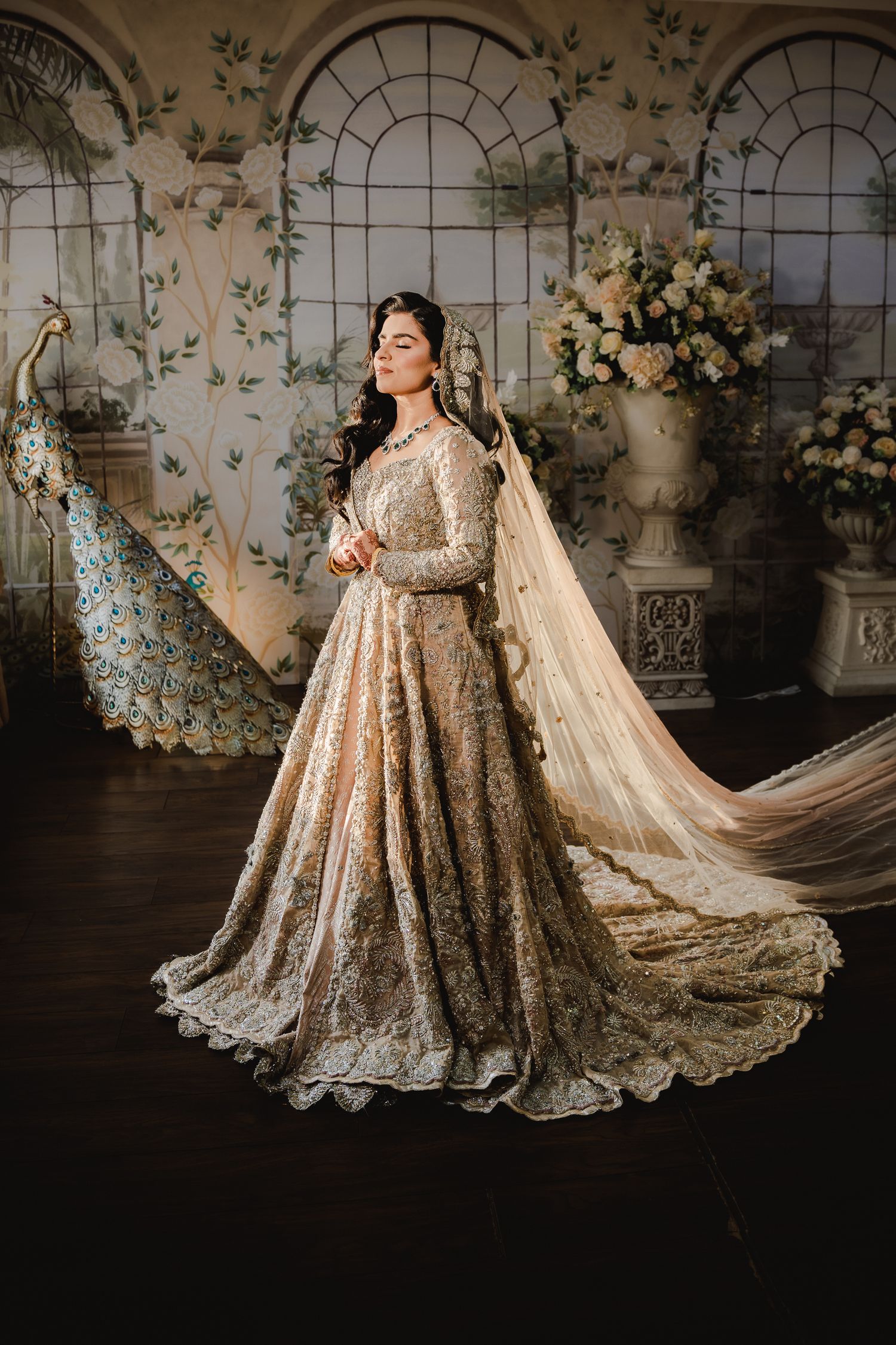 Luxurious champagne wedding gown with intricate details and flowing train in ornate indoor setting.