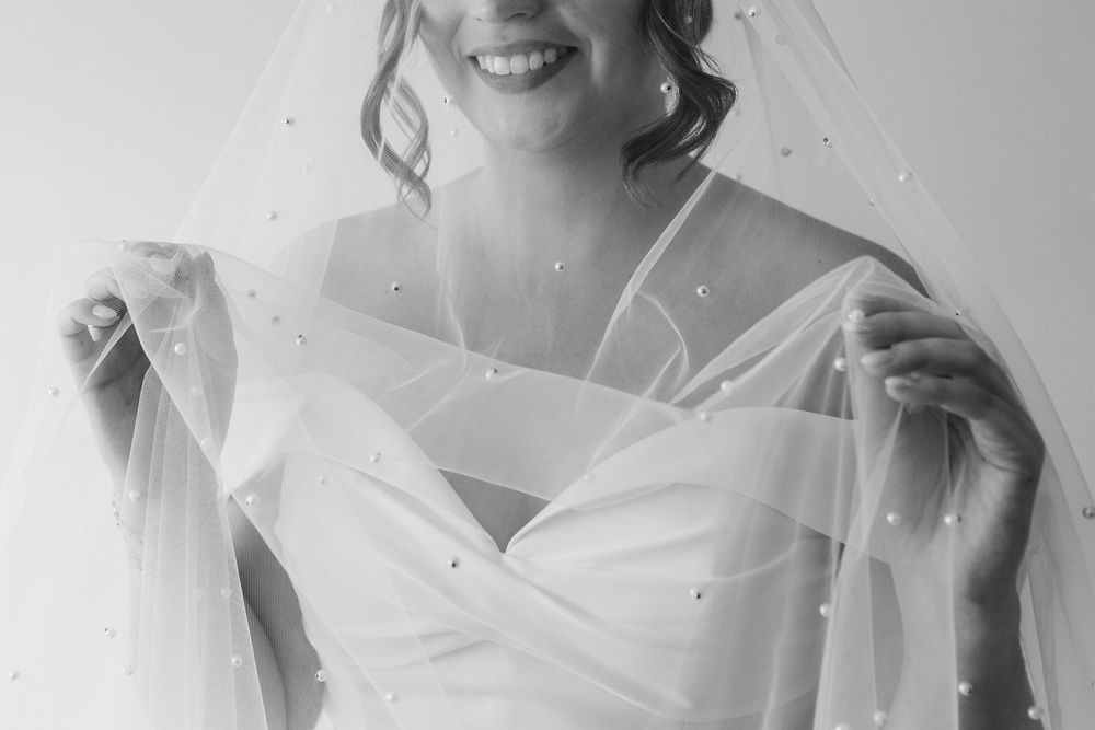 Black and white bride holding a pearl adorned veil